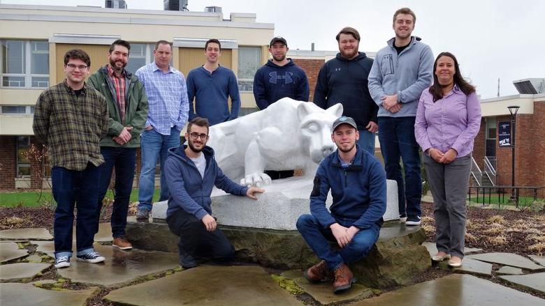 Penn State New Kensington BET students and faculty member stand by lion statue